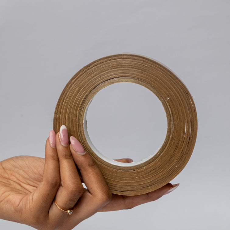 A hand holding a roll of eco-friendly carton tape - a sustainable alternative to sellotape for packaging needs.